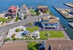 Experience resort-style waterfront living in this beautifully updated legal 2-family home (by CO) with a separate 1-bedroom apartment, ideally located in a cul-de-sac along a canal leading directly to the Great South Bay. Offering nearly 2, 000 sq. ft. of living space with panoramic water views from almost every room, this home is perfect for investment, multi-generational living, or owner-occupied with rental income. The main home features 2â€“3 bedrooms, a renovated bathroom, updated eat-in kitchen with stainless steel appliances, granite counters and door to the outside, a bright living room with gas fireplace and hardwood floors, a family room with French doors to deck, and laundry room. Upstairs offers 2 bedrooms. The second unit includes a vaulted living room with sliders & skylights to a new Trex deck overlooking the canal, an open kitchen with stainless steel appliances and abundant cabinetry, a large bedroom and full bath. A large storage area runs under the main home. Outdoor amenities include new Trex decking, gazebo, patio, new bulkhead, 4 boat slips (1 deeded with seller) and an attached lot creating the perfect yard. Raised after Sandy, low flood insurance. Additional highlights include gas Navien tankless heat, 2 electric meters and a 12-year-old roof. A rare and unique Lindenhurst waterfront opportunity combining comfort, luxury and investment potentialâ€”donâ€™t wait too long for this one!