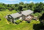 Set in the tranquil landscape in Clinton, this thoughtfully designed residence on 2.81 acres of rolling meadow creates an ideal retreat from city life. The open-concept main level flows seamlessly between the living room, dining area, and kitchen, making everyday living and hosting effortless. Natural light streams through the all-season room, featuring three walls of windows that frame peaceful views of the property. The outdoor spaces invite you to embrace nature, with a bluestone terrace perfect for morning coffee, a deck designed for al fresco dining, and meandering paths through the private grounds. The main level includes two bedrooms and a full bath, while the lower level offers additional living space warmed by a fireplace. Sliding doors on the lower level provide direct outdoor access, complemented by a second full bathroom and generous storage areas.The front porch adds classic countryside appeal, creating a welcoming entrance and an additional spot to take in the serene surroundings. Positioned in a peaceful section of Dutchess County, this 1968 home combines modern layout sensibilities with the enduring appeal of a private countryside setting. Experience the perfect balance of indoor comfort and outdoor living in this Clinton Corners home, close to the many attractions, restaurants and farm markets available in the Hudson Valley.