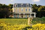 Just a mile and a half south of Millbrook Village, along the scenic stretch of Route 82 where farmland unfolds and county views stretch for miles, a tree-lined driveway winds back from the road to reveal a distinguished country estate. Built in the mid-1990s yet styled with timeless character, this Second Empire Victorian home showcases a sweeping wraparound porch, a classic mansard roof, and intricate dentil molding that capture a bygone elegance. Robust double entry doors open to a grand center hall with soaring 12-foot ceilings. To the right, an office frames sweeping views of the surrounding farmland; to the left, a gracious living room centers on a wood-burning fireplace. A cozy den offers a retreat for quiet evenings, while the formal dining room flows seamlessly to the back patioâ€”perfect for al fresco gatherings. The spacious kitchen features abundant cabinetry, an island, and sun-filled windows framing uninterrupted green vistas. Upstairs, the primary suite includes an ensuite bath, complemented by two additional bedrooms, a full bath, and a second office. A third-floor bonus room offers endless versatilityâ€”ideal for a media lounge, playroom, gym, or game spaceâ€”all surrounded by panoramic views. Set on over five acres, the property is complete with a three-car garage, fenced garden, and meandering walking paths. Less than 90 miles from Manhattan, this home offers the best of country living with easy access to Millbrookâ€™s beloved amenities, including retail and antique shopping, restaurants like Cafe Les Baux, and the much-talked-about House of Stefas, and activities like Innisfree Garden and the Cary Institute.