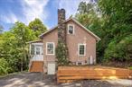This conveniently located two-bedroom, one-bath stucco residence offers significant potential for improvement. Situated on a corner lot just minutes from the Metro North train station, major highways, shopping, and the charming hamlet of Croton Falls, it is ideal for commuters. Key features include hardwood flooring, a mantled stone fireplace, and an enclosed heated front porch adding additional living space. This property presents an excellent opportunity as a rental or year-round home for buyers seeking to add value through renovation.