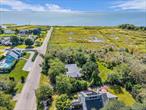 Nestled within a tranquil enclave of Bellport, this thoughtfully designed single-level ranch style home offers a blend of privacy, space, and potential on 1.37 acres. Backing onto 35 acres of protected land to the south and west, the property provides a serene natural setting with the possibility for future water views. Boasting 1, 750 square feet of interior living space, this home features three bedrooms and two full bathrooms, including a primary bedroom with an en-suite bath. A courtyard entry sets a welcoming tone, flowing into a sunlit living room enhanced by a vaulted ceiling and sliding glass doors that open to an expansive paver patio crowned with a pergola. The den, featuring built-in cabinetry and a cozy fireplace, also offers seamless access to the backyard, creating a harmonious indoor-outdoor connection ideal for entertaining.At the heart of the home, a pass-through galley kitchen is outfitted with stainless steel appliances and granite countertops, comfortably connecting to both an informal dinette and a formal dining room. A one-car attached garage, dedicated laundry space, newly replaced roof, and mature landscaping add to the practical appeal. The location offers unmatched access to the charm and culture of the surrounding community, with nearby highlights including local organic farms, marinas, a vibrant arts scene, and attractions such as The Gateway Playhouse, and the Bellport Country Club and Golf Course. This residence presents an exceptional opportunity for those looking to personalize a solid home in an established and scenic neighborhood. The potential to create a modern coastal retreat in harmony with its natural surroundings awaits its next owner.