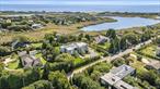 Perfectly positioned south of the highway in Bridgehampton, this architectural showpiece sets a new benchmark for modern Hamptons living. Designed by McDonough & Conroy and brought to life by Hampton Builders, Inc. and Fineo Development Group, the residence blends sophisticated design with effortless functionality. Interiors curated by Leslie Norton Fineo of LNF Interiors and landscape design by Dean Gomolka enhance the homeâ€™s clean aesthetic, with Chris Mead of English Country Home completing the vision through expert staging.The exterior presents a refined palette of limestone, stucco, and custom mahogany siding, while walls of glass frame sweeping views of the ocean, bay, and Mecox Pond. Inside, 7, 800&#177; square feet of living space are arranged with an open, modern flowâ€”bathed in natural light and curated with meticulous attention to detail.The main level centers around a stunning chefâ€™s kitchen with dual islands, marble finishes, and top-tier appliances, complemented by a separate catering kitchen. Expansive living and great rooms feature dual-sided fireplaces, seamlessly connecting to the outdoor entertaining spaces. A formal dining room, en suite guest suite, junior primary with terrace, mudroom, and pool cabana with full bath complete this level.Upstairs, the primary suite is a true retreat, offering a private sitting area, spa bath, oversized custom closet, and a private terrace. Three additional en suite bedrooms, a second laundry, and rooftop access expand the lifestyle offerings, where an expansive roof deck affords panoramic ocean-to-bay vistas.Outdoors, the amenities are equally exceptional: a 20&rsquo; x 40&rsquo; infinity-edge heated gunite pool with in-pool spa, an outdoor kitchen, and sun-drenched patio framed by lush landscaping. A three-car garage and a private 0.92&#177; acre cul-de-sac setting complete this estate.Just moments from world-class beaches, vineyards, and Bridgehamptonâ€™s premier shopping and dining, this residence is a rare opportunity to own a south-of-the-highway sanctuary that blends cutting-edge architecture with timeless Hamptons luxury.