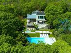 In a class by itself, New to Market, exquisite Malibu Style Modern Contemporary perfectly suited on a meticulously well-kept shy 2-acre parcel with Pool and Tennis offering the Ultimate in Hamptons Resort Style Summer living. Magnificently positioned and perched high above is where you&rsquo;ll find this exceptional Hamptons 4 level Modern bathing in full privacy and greenery with its commanding views of the full-sized North/South Tennis and its oversized 52x18 heated Saltwater Gunite Pool. Here summer never ends with its pool and jacuzzi wrapped in white marble and sprawling green lawns which take center stage all summer long. Boasting 6725 sqft of luxurious open and modern resort style living spaces on 4 levels which feature soaring ceiling heights, an abundance of natural light and its expansive sliding glass doors which magically blend the indoor and outdoor spaces effortlessly creating the ultimate Hamptons entertaining space. Guests of all ages will enjoy the well-appointed 4 Guest ensuite beds found on 2 private levels plus the additional private Owners Suite which occupies the entire 3rd floor, complete with Resort Style Spa bath and breathtaking views. For the discerning Chef, a fully outfitted Chefs Kitchen with its professional high-end stainless-steel appliances and large center island sit ready and waiting to deliver the ultimate dining experience while enjoying marvelous Tennis and Poolside views. A whole range of amenities are available on level 1 that enliven this unequaled Hamptons Summer Getaway, which include a Cinema room, Fitness center, sprawling lounge and its well-furnished wet bar. While serenity enwraps this captivating Hamptons retreat, it lies in superbly convenient proximity to world renowned Sag Harbor, Bridgehampton and Southampton shopping districts and its beloved Ocean Beaches.,