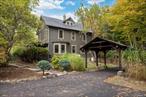 This historic Woodstock home, complete with a legal short-term rental license, is ready for its next chapter. Just a short distance from the iconic village green and the heart of Woodstock, this recently restored 1897 Arts and Crafts farmhouse offers both privacy and convenience on one of the town&rsquo;s most desirable streets - a truly rare combination that seldom becomes available.The charming property blends historic character with thoughtful updates, featuring a composite slate roof, copper-roofed addition with gutters, original wide-plank wood floors, and distinctive custom Pella windows, which are an architectural focal point and often the first feature guests remark on.Set on 1.49 landscaped acres, this special property invites you to wander through meandering paths, patios, and stone walls. Outdoor living is a highlight, with a wood pergola and harvest table overlooking a seasonal stream, along with a built-in cooking area and grill. The Brazilian ironwood wraparound deck, complete with hot tub, offers a spa-like space to relax.The beautifully landscaped and paved front garden leads to a welcoming porch - perfect for morning coffee in an Adirondack chair or on a swing.Inside, the entry hall and impressive oak staircase open to a cozy living room where sun pours through the bay windows and a modern gas fireplace adds warmth. At the back of the home, a dining room and peaceful sunroom have French doors opening onto the deck - perfect for effortless summer entertaining.The kitchen features cherry cabinetry, honed granite counters, Bertazzoni appliances, and generous pantry space. A full bathroom and laundry complete the first floor.Upstairs, you&rsquo;ll find three bedrooms and a full bath with a clawfoot tub, and a hallway landing that frames a mountain view. Topping it all off, the third floor adds two additional rooms, each with its own mini-split for heating and cooling.The well-kept stone basement houses a high-efficiency Buderus boiler and well-maintained mechanicals.Blending upscale custom details with historic charm, this special property offers easy living, plenty of space, and the option to personalize to your taste - all just minutes from Woodstock&rsquo;s vibrant town center.
