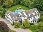 Privately set behind a gated entry on a maturely landscaped acre, just 65 miles from New York City, this custom-built estate located in East Moriches offers more than 4, 700+/- square feet of refined living across three levels with an additional 1, 300sqft finished lower level. Designed with historic architectural detailing and modern amenities, the home balances elegance, warmth, and functionality in every room. A dramatic double-height foyer introduces the residence, leading into elevated living space with 9&rsquo; coffered ceilings on the main level, hand-plastered walls, custom woodwork, and hand-painted finishes throughout. The chef&rsquo;s kitchen is a centerpiece, complete with Viking and Subzero appliances, custom hand-painted flooring, two sinks, extensive counter seating, and an oversized breakfast room overlooking the grounds through floor-to-ceiling windows. Adjoining spaces include a butler&rsquo;s pantry, formal dining room, sitting room, and an expansive living room anchored by a gas fireplace, creating a seamless flow for entertaining. The second floor, with 8&rsquo; ceilings, offers four bedrooms including a sun-filled primary suite with its own private terrace. The spa-like primary bath is finished with radiant-heated floors, marble tiling, an oversized dressing room, and a steam shower. In total, the home offers two full bathrooms and three powder rooms. On the lower level, 10&rsquo; ceilings frame a fully finished basement with a gym, media room, bathroom, ample storage, and flexibility for future expansion. The third floor provides unfinished space with further potential, while the heated three-car garage with custom glass doors includes a finished loft with a powder room-ideal for a home office or studio. A formal foyer and a mudroom with laundry and storage add both function and convenience. Outdoors, the property is designed as a private sanctuary. A heated gunite saltwater pool with waterfall feature and whirlpool spa is surrounded by a brick patio and outdoor shower. An elevated, vegetable garden and orchard provide a lush, productive landscape. Mature trees and professional plantings enhance the sense of privacy, offering a sense of calm and beauty. This property also includes buy-in rights to nearby Hamptons beaches, expanding the lifestyle this estate affords beyond the gates and into the shoreline community. Every detail reflects thoughtful craftsmanship and timeless appeal, combining gated seclusion with versatile living and effortless access to the city. **Seller has filed for and is in the process of obtaining an updated Certificate of Occupancy to reflect the finished basement and finished room above the garage. Current square footage is broken down as follows: Main House (3, 786 sq. ft.), Basement (1, 351 sq. ft.), and Office/Loft (938 sq. ft.).**